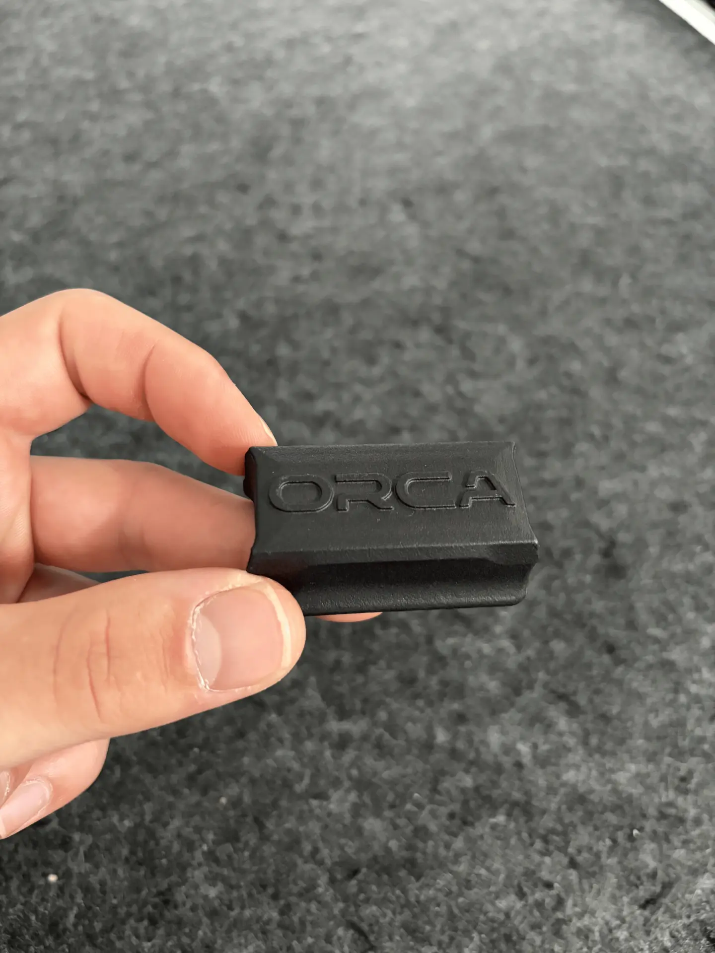 ORCA sensor held between two fingers, showing the engraved ORCA logo