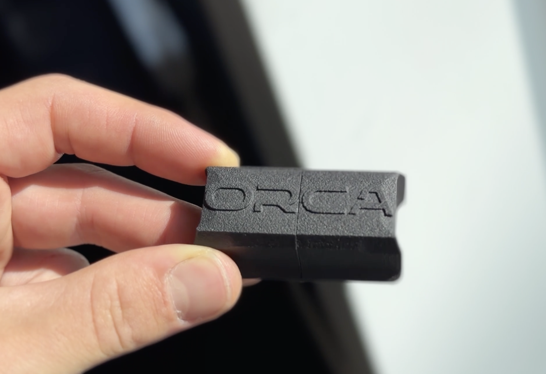 ORCA sensor held between two fingers, showing the engraved ORCA logo